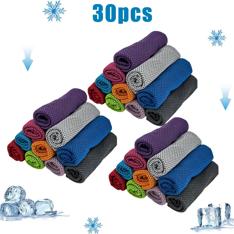 A collection of 30 purple, blue, and gray cooling microfiber towels arranged in a pyramid shape next to ice cubes.