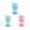 Reusable silicone collapsible coffee cups with lids in white, blue, and pink colors.