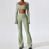 A woman models a light sage green performance tracksuit set consisting of a cropped top and matching full-length pants.