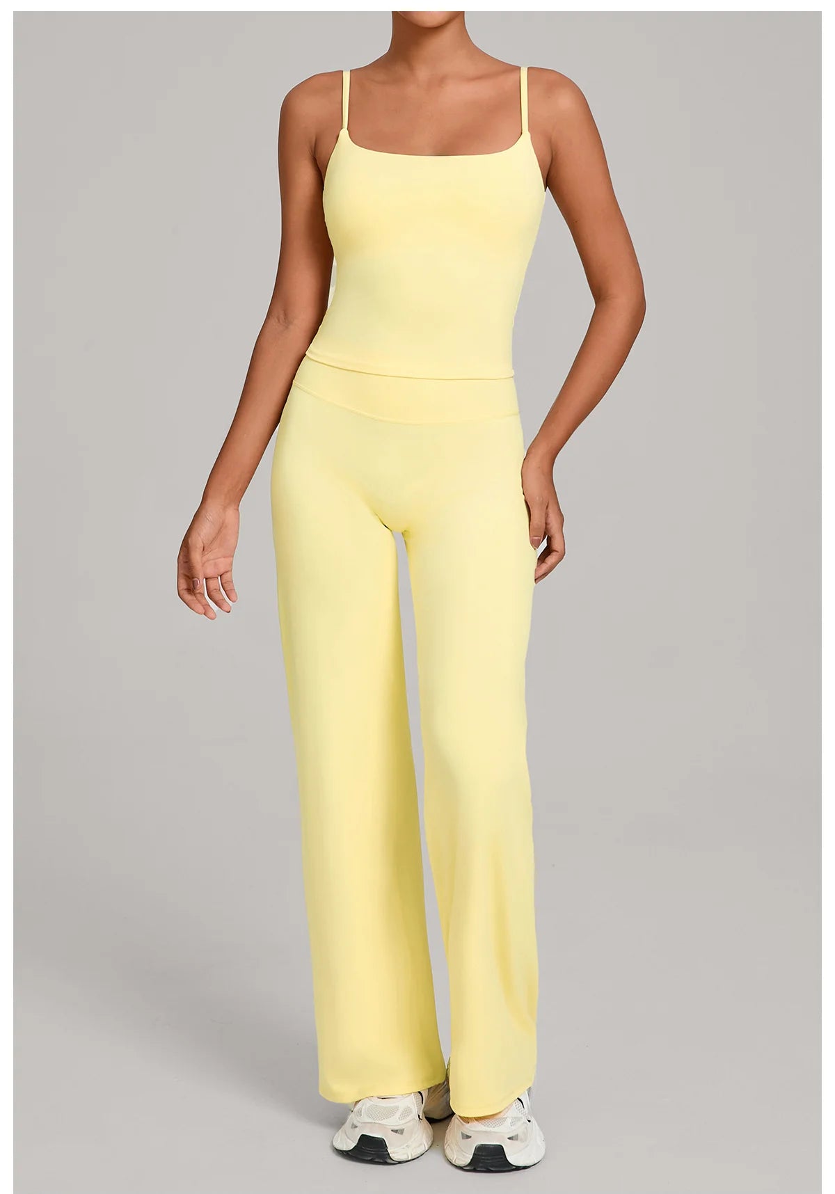 A woman models a yellow high-waist yoga and fitness tracksuit set top and pants.