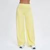 A woman is wearing light yellow high-waist flared yoga pants and white athletic shoes.