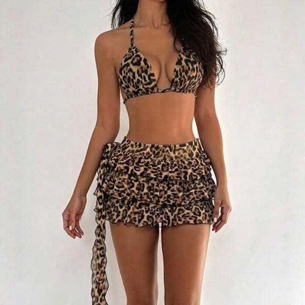 A woman models a leopard print three-piece bikini set consisting of a crop top and a mini skirt.