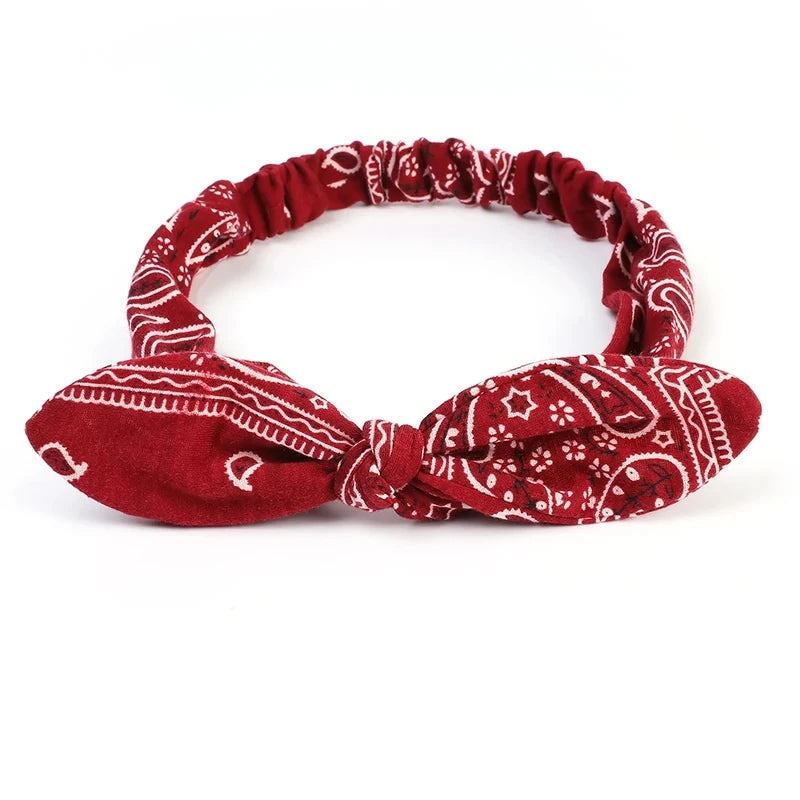 A red paisley patterned elastic hair headband tied in a bow.