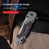 A close-up of a black multi-functional folding survival knife clipped onto a brown jacket.