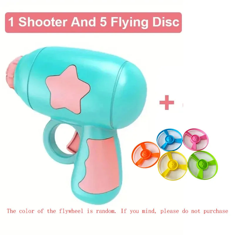 Pistolet jouet bleu avec poignée rose et cinq disques colorés en vol.