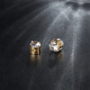 A pair of gold-toned magnetic cubic zirconia stud earrings resting on a dark surface.