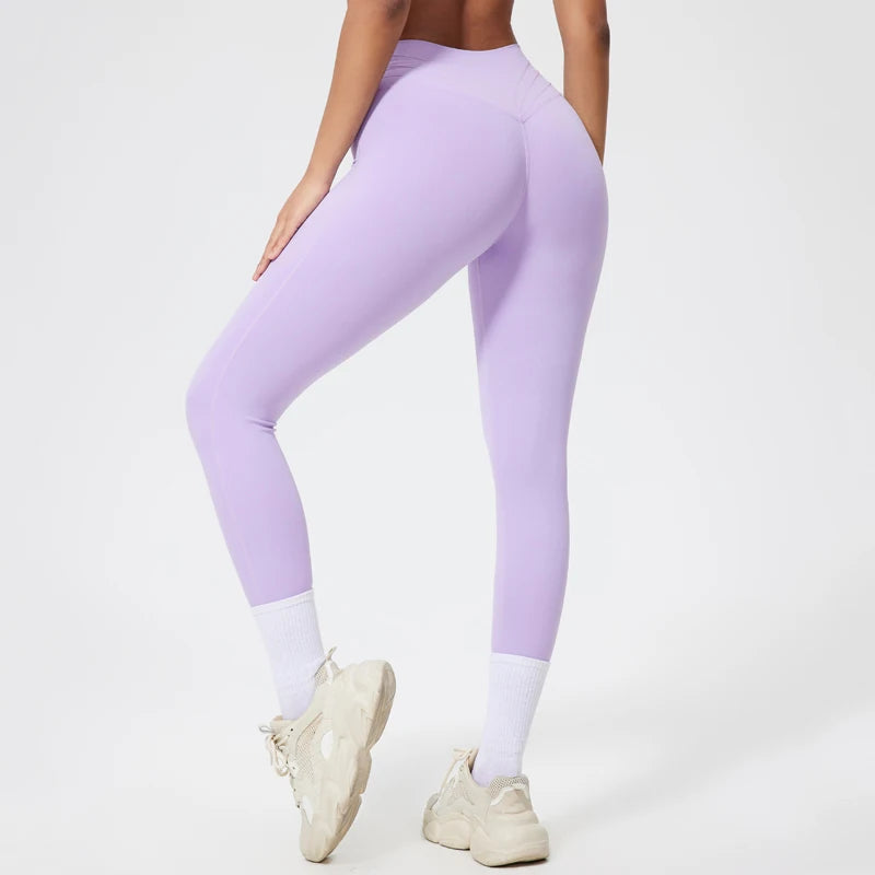 Person in seamless purple yoga leggings and white socks, standing in a neutral pose.
