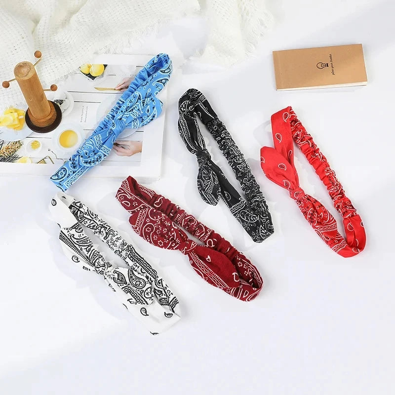 A collection of boho paisley elastic hair headbands in blue, black, red, and maroon are displayed on a white surface.