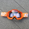 Lunettes de moto tout-terrain orange avec inserts en mousse blanche posées sur une surface grise.