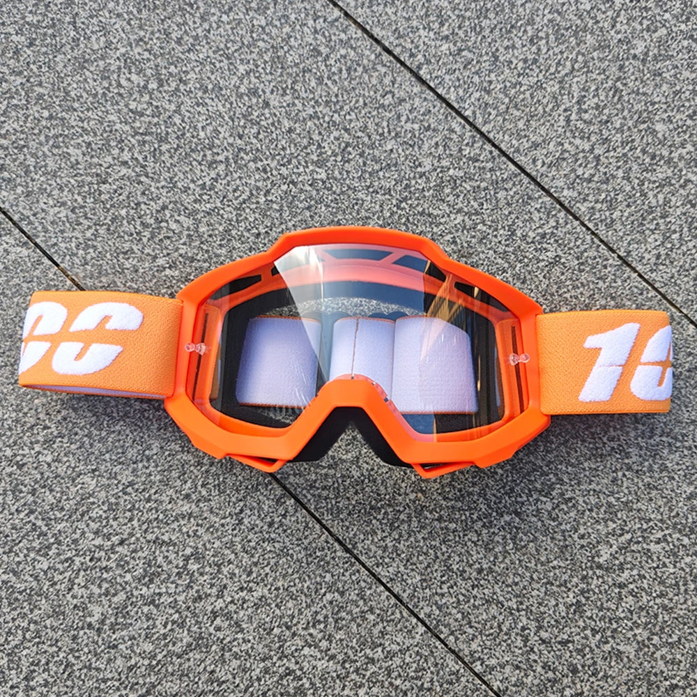 Lunettes de moto tout-terrain orange avec inserts en mousse blanche posées sur une surface grise.