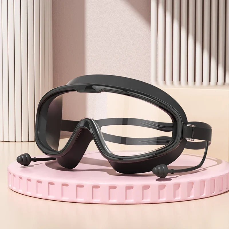Un par de gafas de natación negras antiempañantes sobre una superficie rosa.