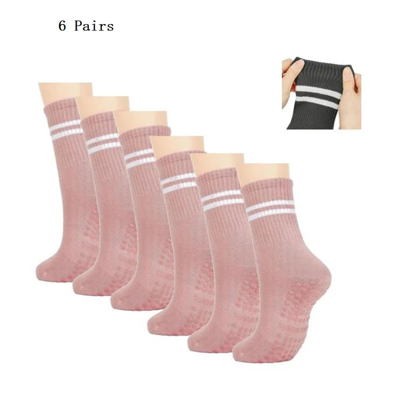 Six pairs of pink grip socks with white stripes shown next to a hand wearing one pair.