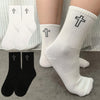 A close-up of white and black men's high-cut breathable casual crew socks featuring a cross design.