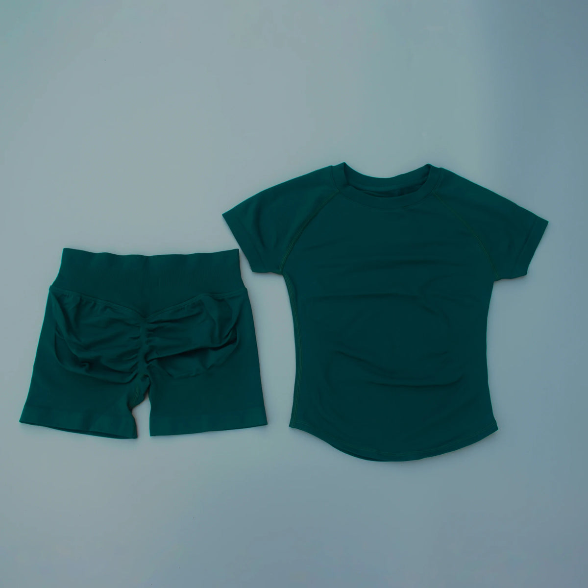 Ensemble de yoga et fitness uni, couleur teal foncé, pour femmes, comprenant un haut à manches courtes et un short assorti.