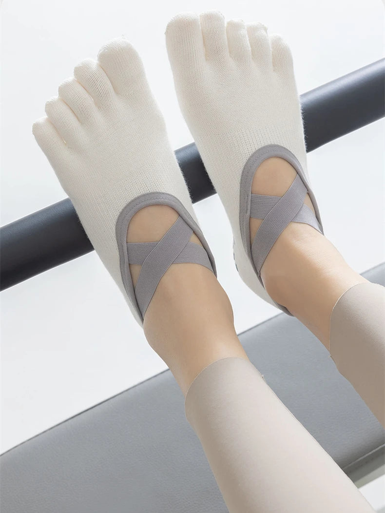 Pair of light gray five-finger invisible yoga and fitness socks worn on feet