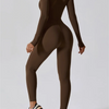 Model trägt einen dunkelbraunen, langärmeligen, figurbetonten Yoga-Jumpsuit.