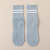 A pair of light blue non-slip yoga socks with white stripes and textured soles.