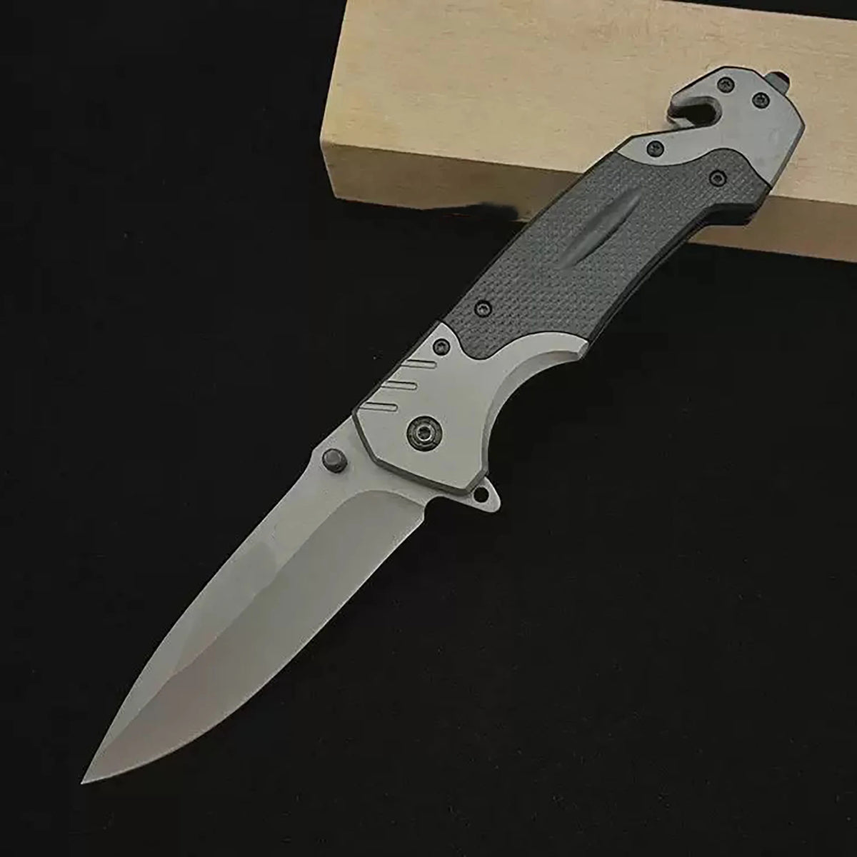 A silver multi-functional folding survival knife resting on a wooden surface.