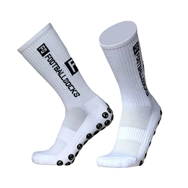 A pair of white football socks with black anti-slip silicone grips on the sole.