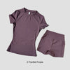 Un conjunto de tops y bottoms de yoga morados de talle alto para mujeres, exhibido sobre un fondo gris claro.