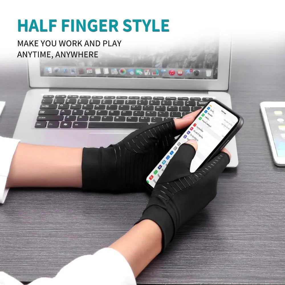 Black half finger compression gloves worn on a hand holding a smartphone next to a laptop.
