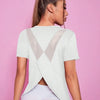 A woman wearing a white breathable summer yoga and fitness t-shirt with a sheer V-neck detail.
