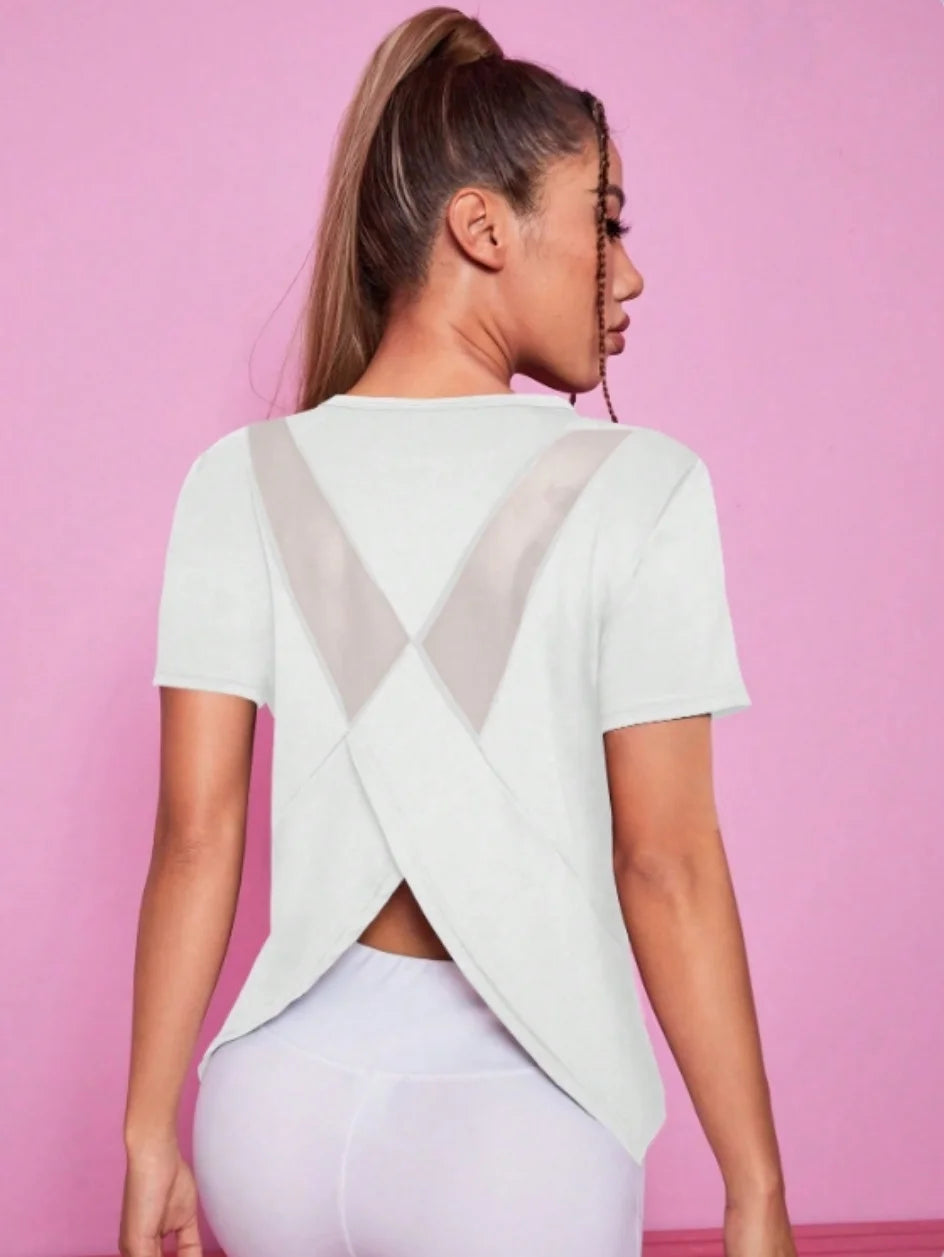 A woman wearing a white breathable summer yoga and fitness t-shirt with a sheer V-neck detail.