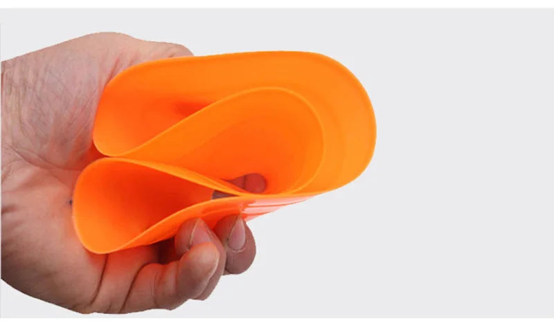 A hand holds an orange soccer training disc cones set.