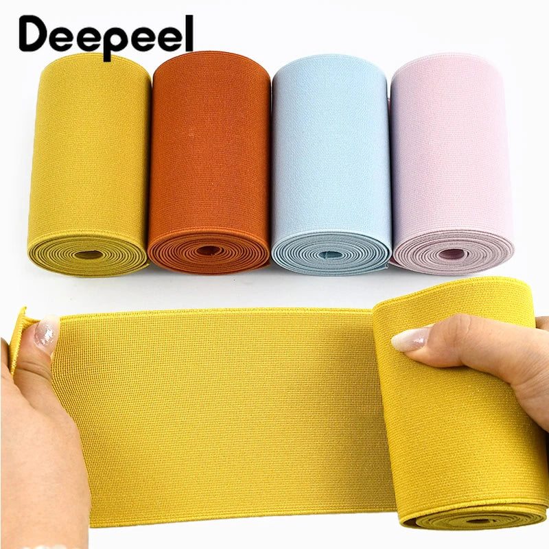 A set of colorful elastic bands in yellow, orange, light blue, and pink are displayed alongside a rolled band.