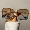 A hand holds a pair of retro two-tone gradient sunglasses with light brown frames and tinted lenses.