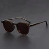 A pair of brown tinted retro round sunglasses resting on a dark surface.
