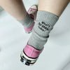 A close-up of a woman's leg wearing gray embroidered cotton socks with pink Converse shoes.