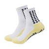 Ein Paar weiße sportliche Grip-Socken mit gelben Akzenten und schwarzen Punkten.