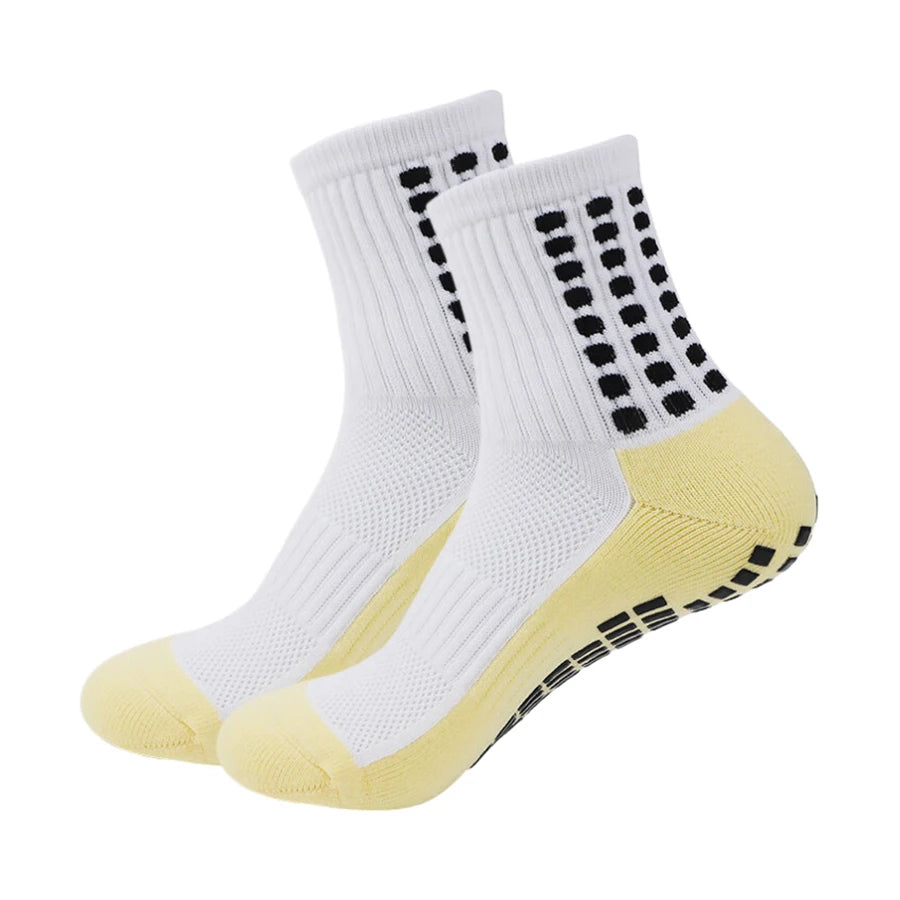 Ein Paar weiße sportliche Grip-Socken mit gelben Akzenten und schwarzen Punkten.
