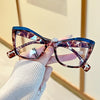 A hand holds a pair of vintage color block blue light blocking eyeglasses with a marbled brown frame.