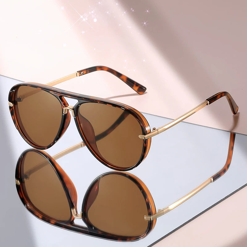 Pair of brown tortoiseshell gradient aviator sunglasses resting on a light surface.