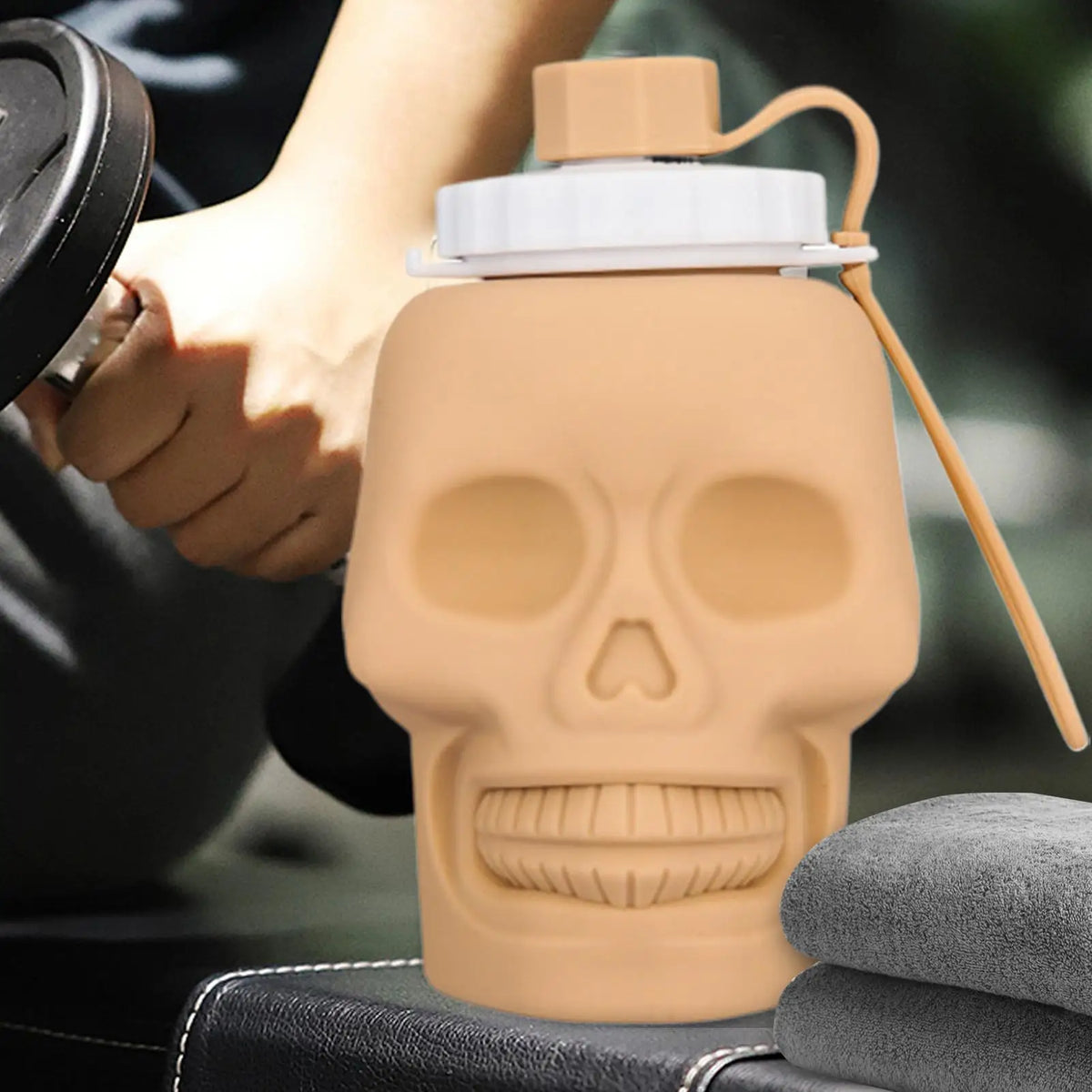 A beige skull-shaped leakproof foldable sports water bottle is being held by a hand.