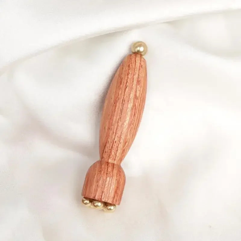 A wooden massage stick with brass lotus eyes, shown against a white background.