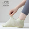 A hand is putting on a light green mesh yoga sock for women.
