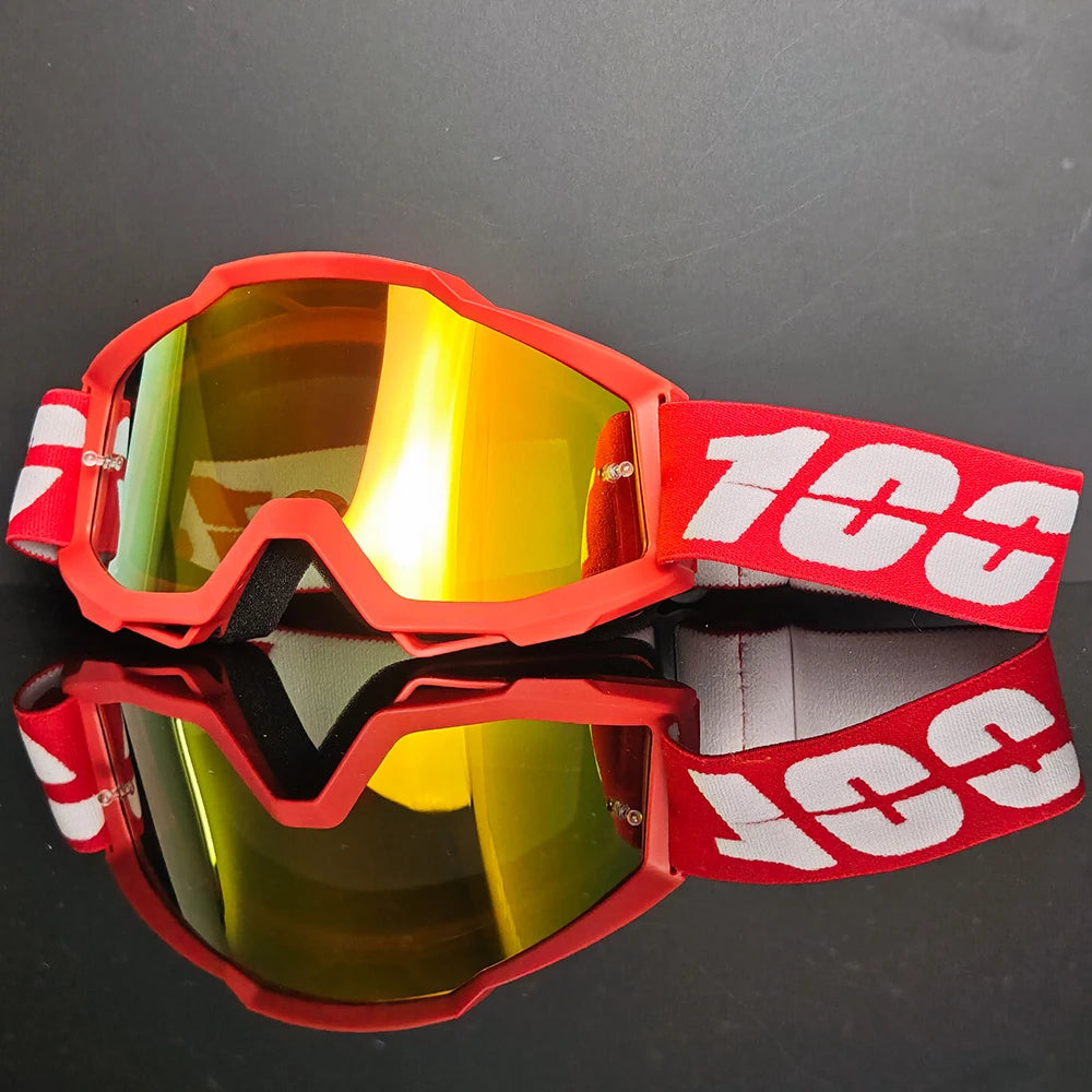 Une paire de lunettes de conduite tout-terrain rouges avec des verres orange et du texte blanc sur la sangle, posée sur une s