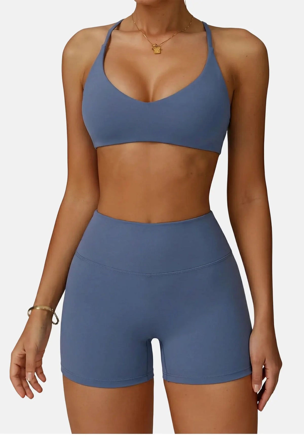 A woman wearing a solid blue high-support sports bra and matching athletic shorts.