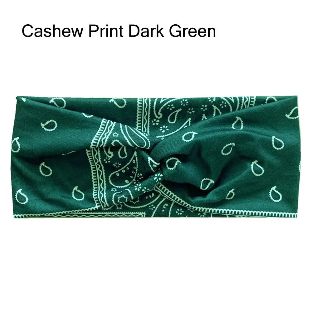 Diadema de tela verde oscuro y elástica con estampado paisley y de hojas blancas.