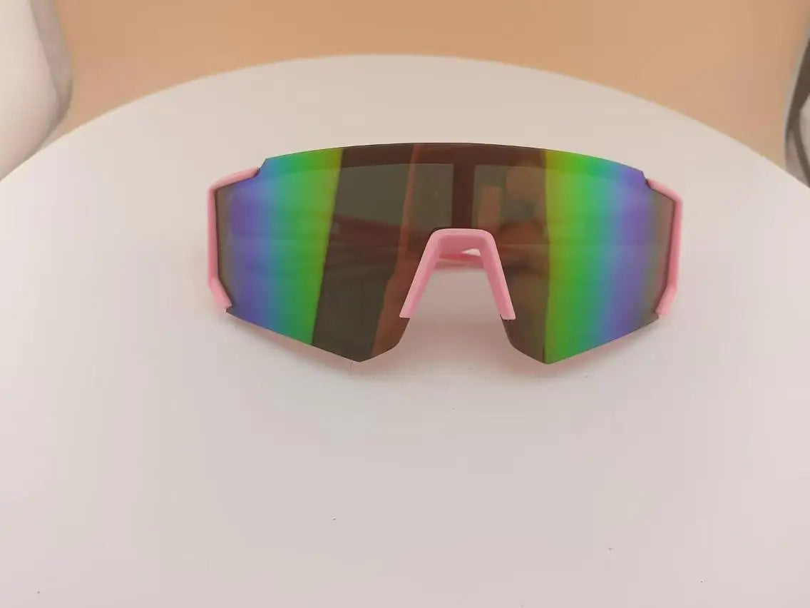 Pink-framed sports sunglasses with mirrored green and purple lenses resting on a white surface.