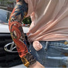 Una persona con una blusa rosa muestra una manga de brazo estampada en naranja y negro en su antebrazo.