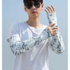 Junger Mann modelliert lose Ärmel mit Tarnmuster vor blauem Himmel.