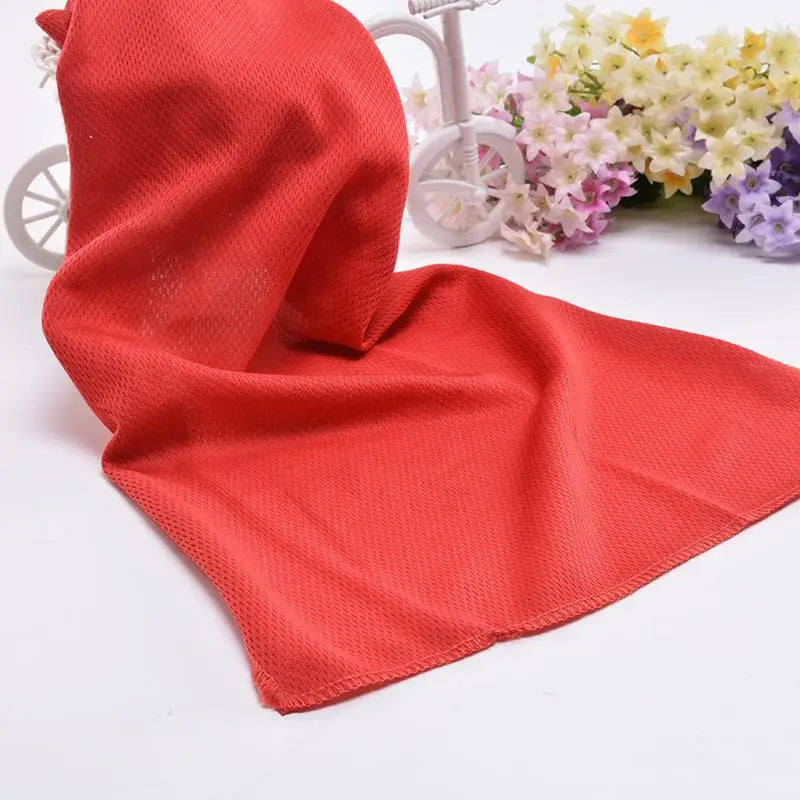 Serviette de refroidissement rouge corail circulaire drapée à côté d'un vélo et d'un arrangement floral.