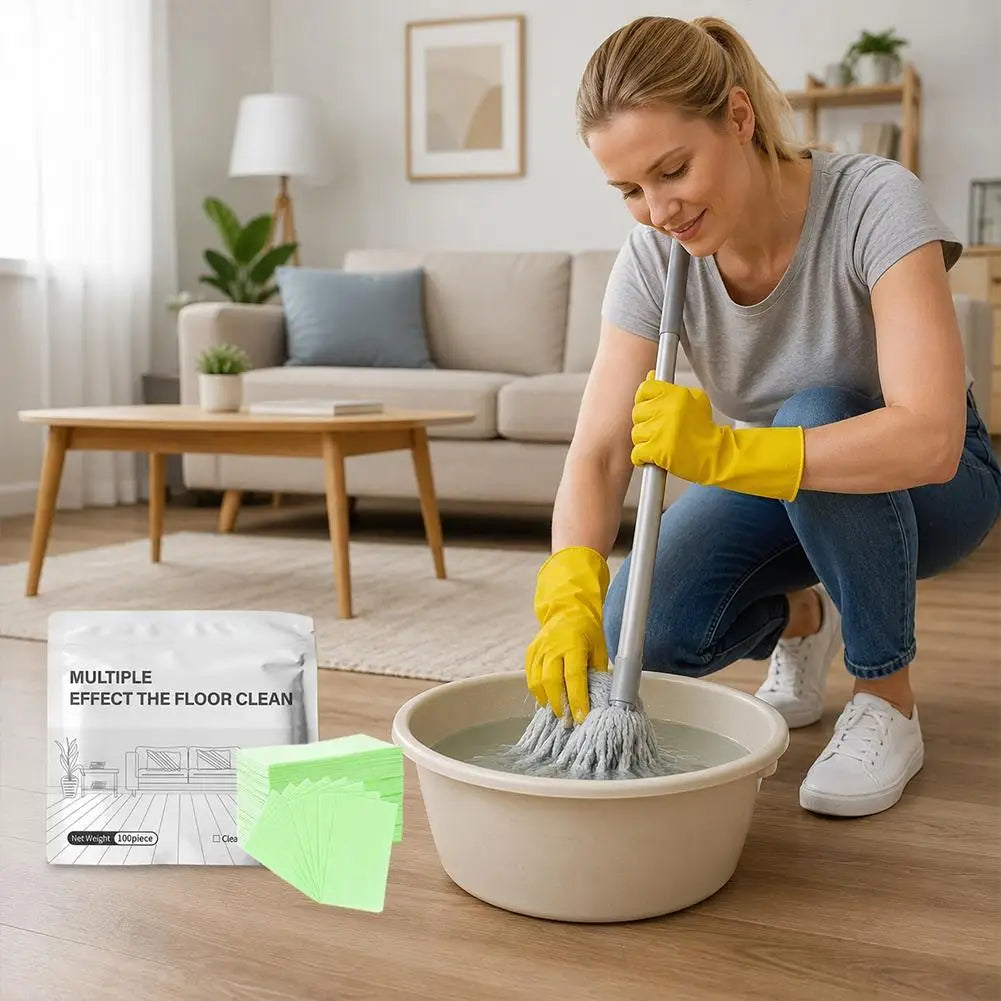 A woman is mopping a floor with a cleaning tool and yellow gloves, with a package of Aroma Floor Cleaning Tablets nearby.