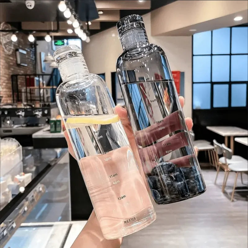 A hand holds an elegant leakproof insulated water bottle with a time scale, showing various time points on the glass.