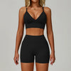 Eine Frau modelliert ein schwarzes, nahtloses Sport-Yoga-Set mit Crop-Top und figurbetonten Shorts.