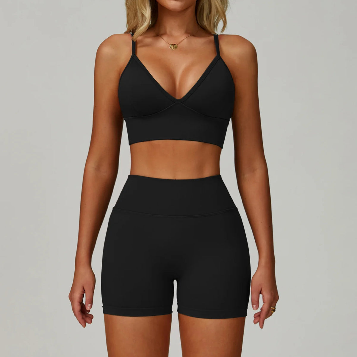 Eine Frau modelliert ein schwarzes, nahtloses Sport-Yoga-Set mit Crop-Top und figurbetonten Shorts.